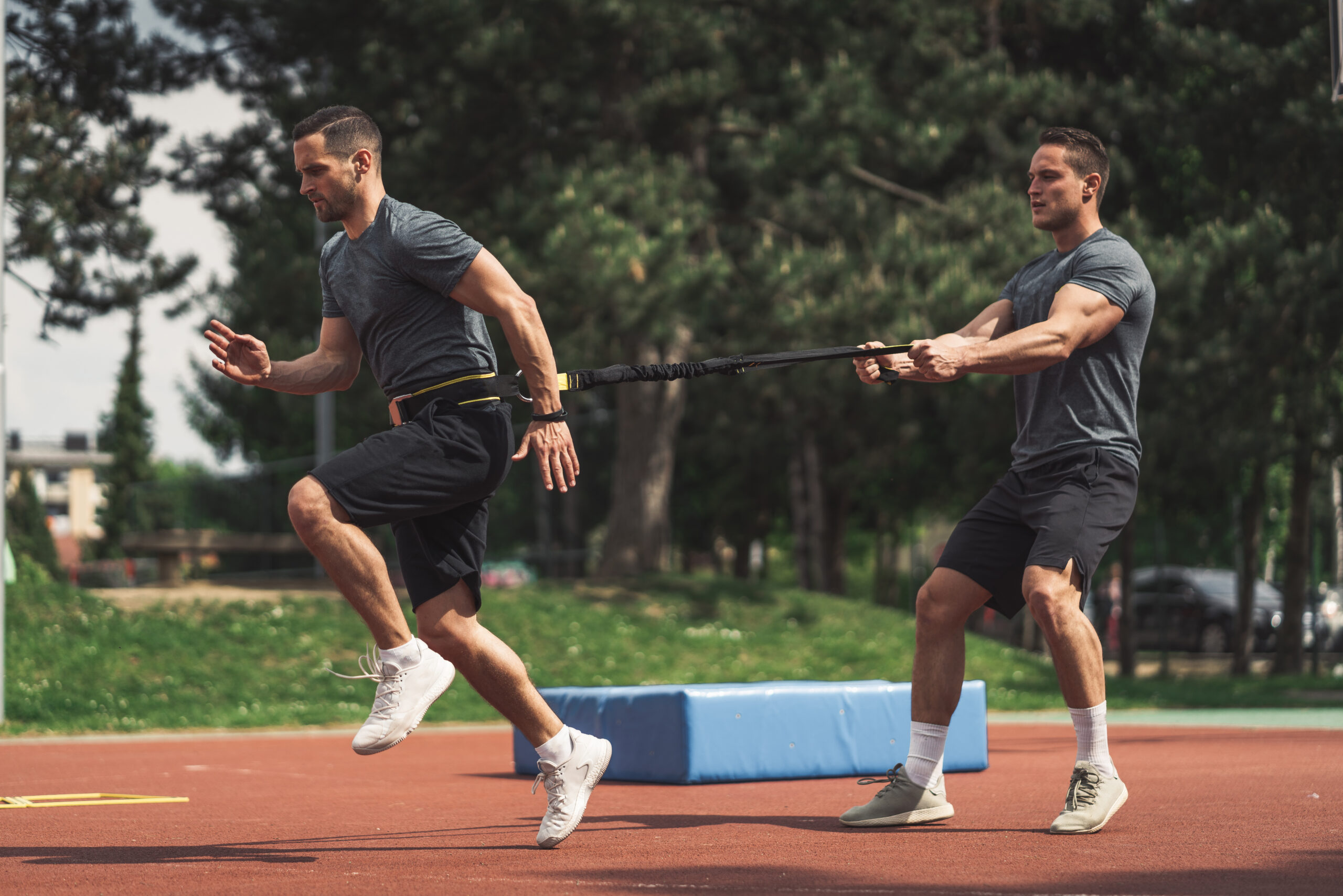 Fit athlete training on a stadium with resistance bands.