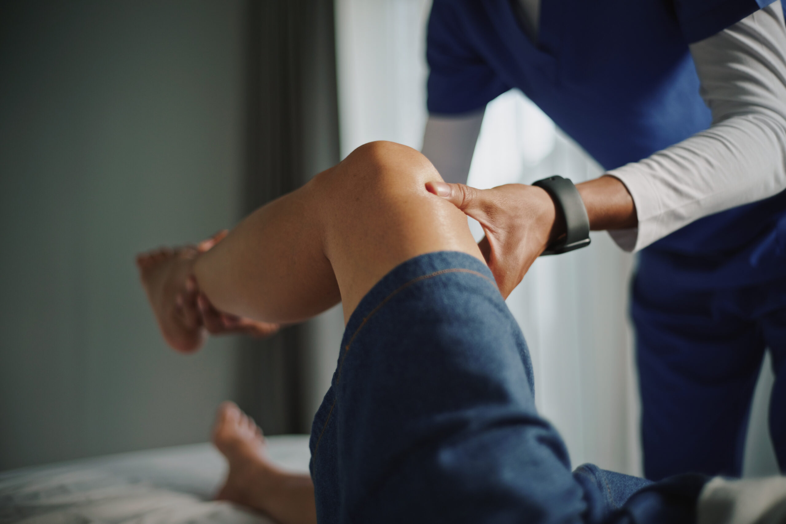 Physical therapist examining knee and leg.