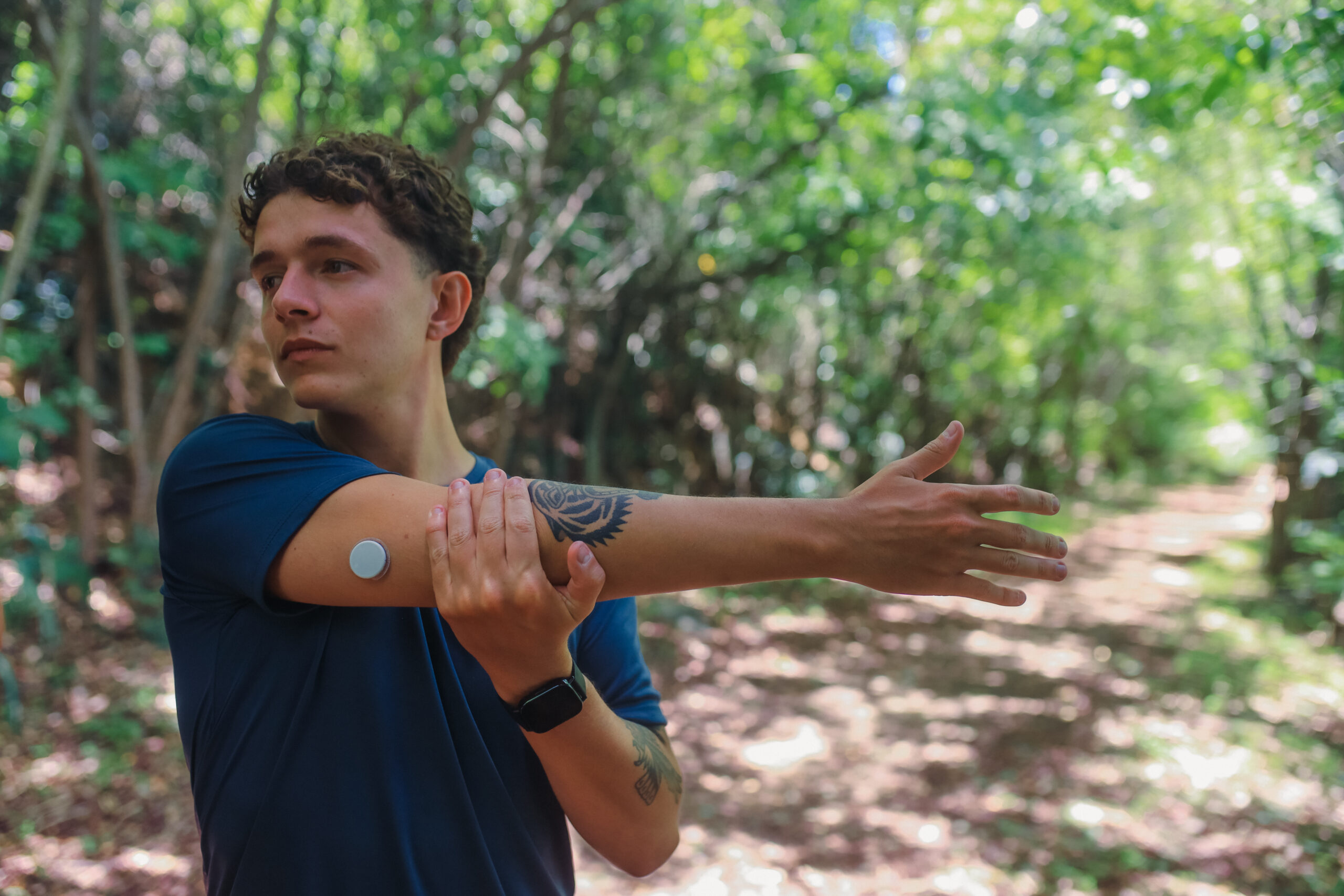 Young Man with a Diabetes Sensor Stretching During a Run