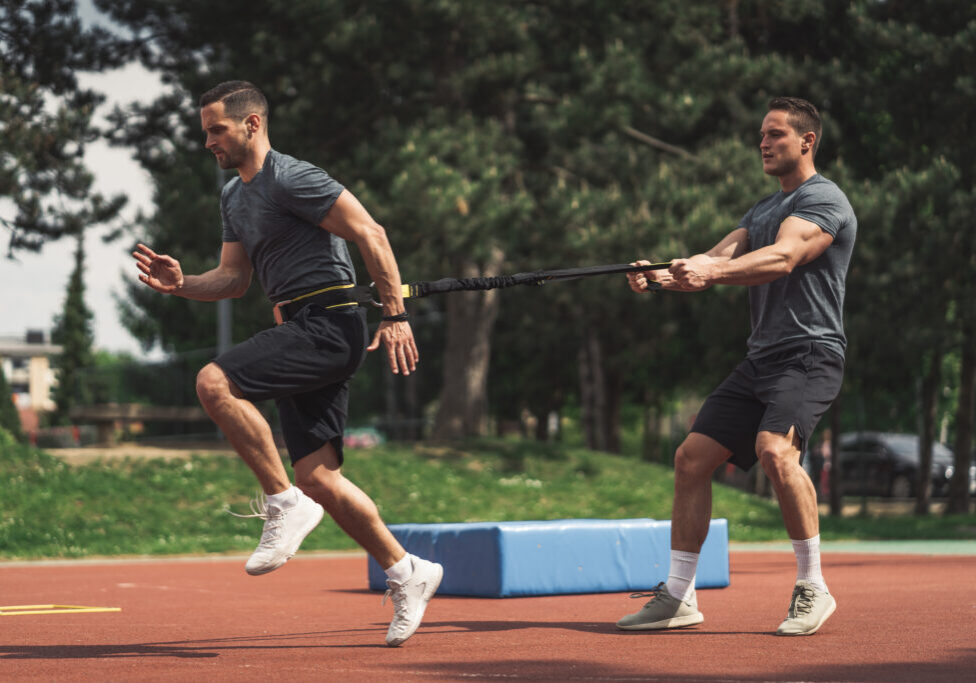 Fit athlete training on a stadium with resistance bands.