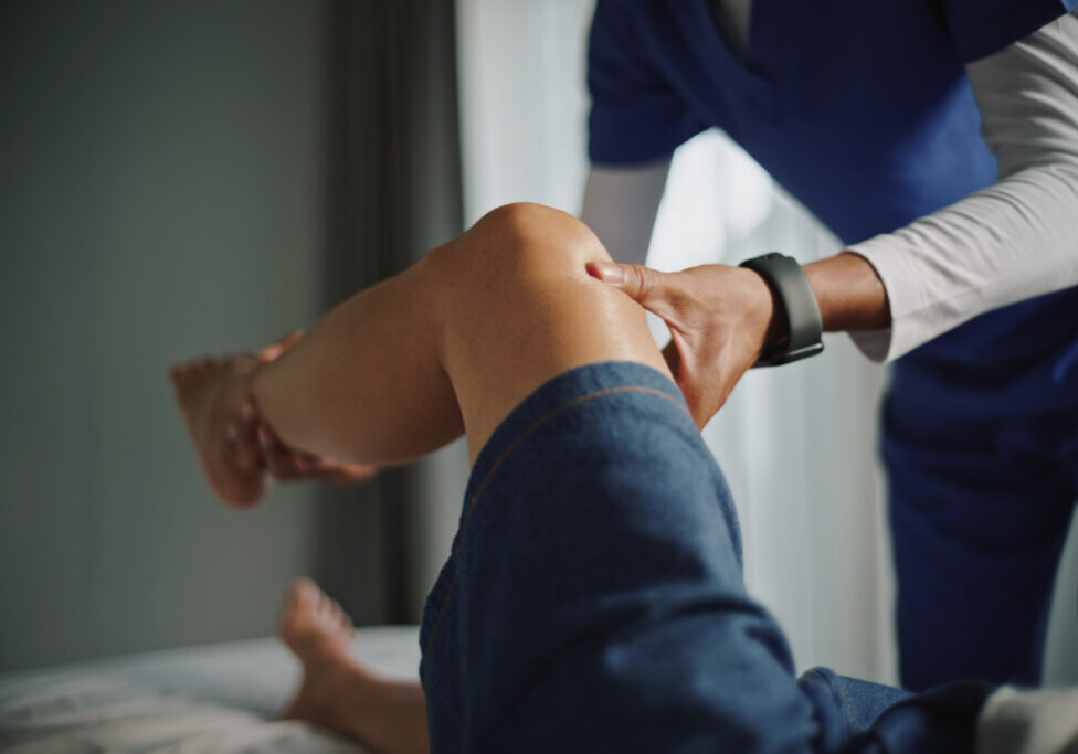 Physical therapist examining knee and leg.