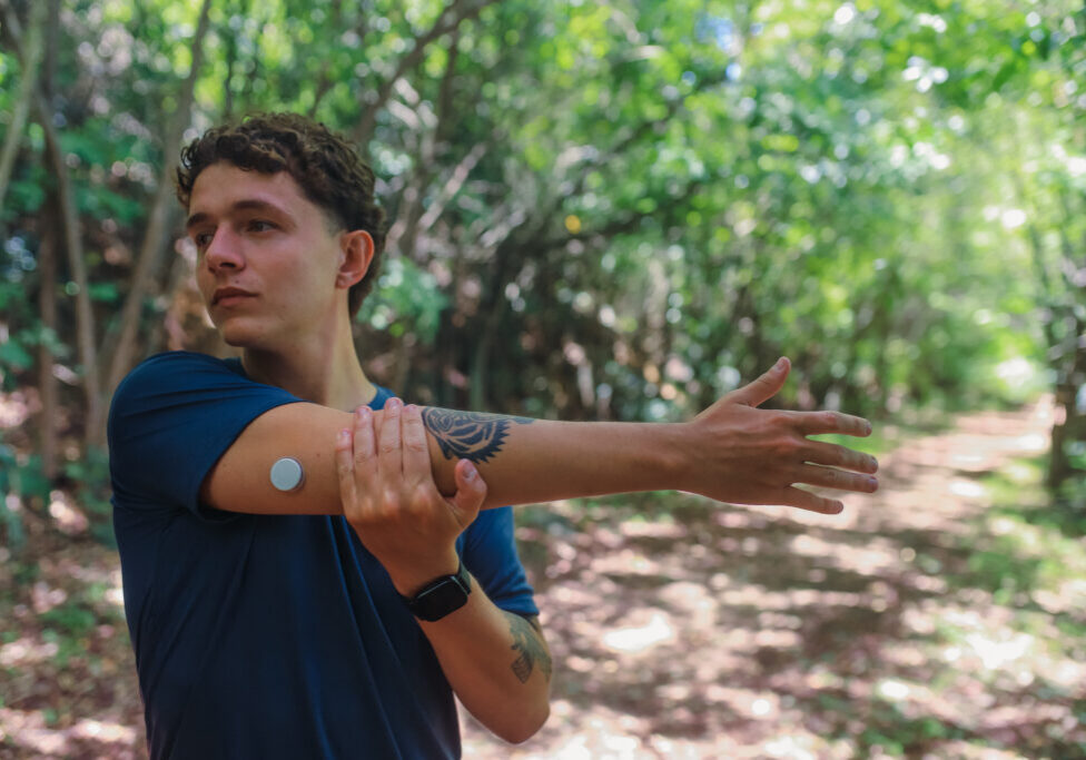Young Man with a Diabetes Sensor Stretching During a Run